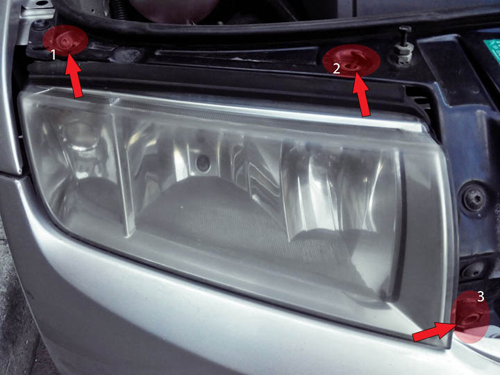 Отворачивание болтов крепления фары автомобиля Skoda Fabia I