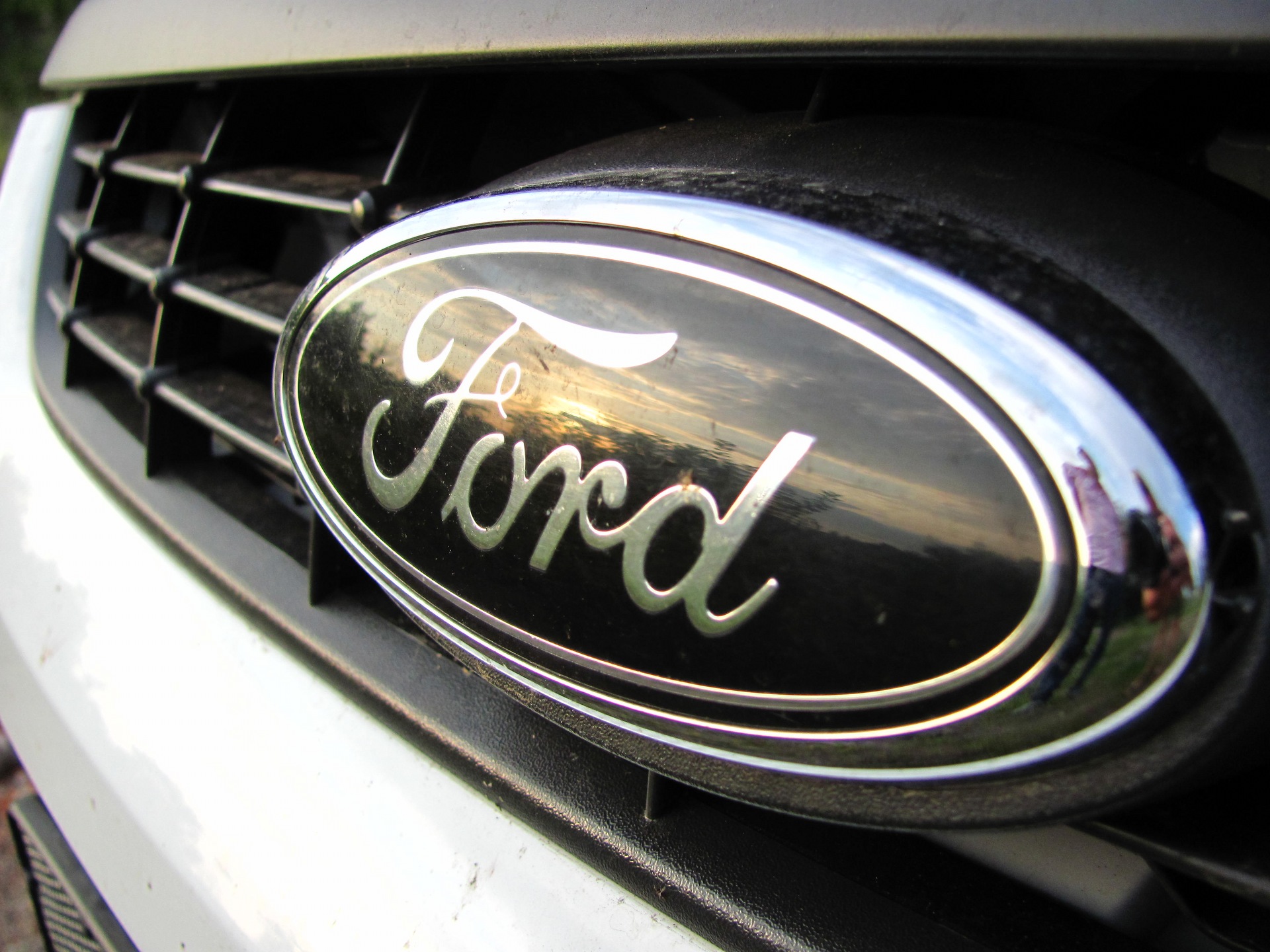 Эмблема, под которой находится личинка замка капота Ford Focus 2